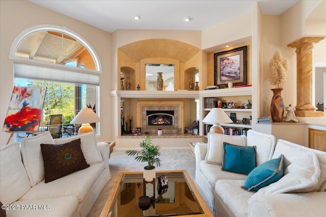 living area featuring a tile fireplace, ornate columns, and recessed lighting