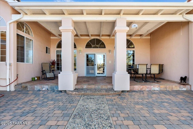 view of exterior entry with a patio and stucco siding