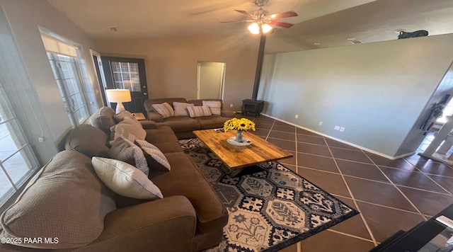 tiled living room with a wood stove and ceiling fan