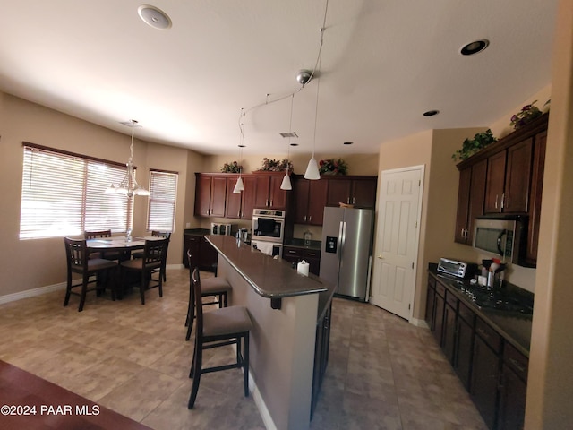 kitchen with a center island, stainless steel appliances, a kitchen breakfast bar, a notable chandelier, and pendant lighting