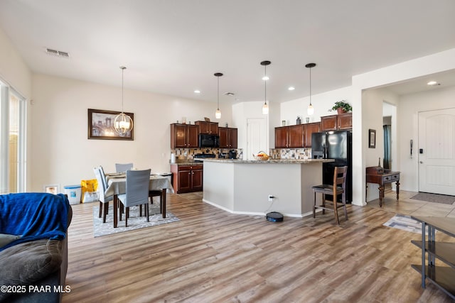 kitchen featuring tasteful backsplash, visible vents, black appliances, and open floor plan