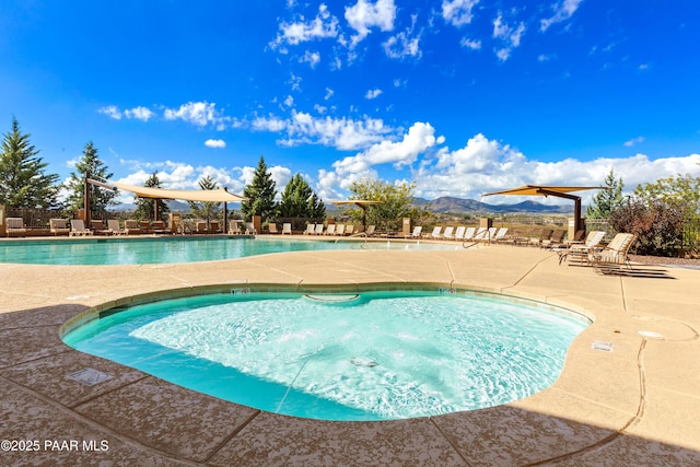 community pool with a mountain view, fence, and a patio area
