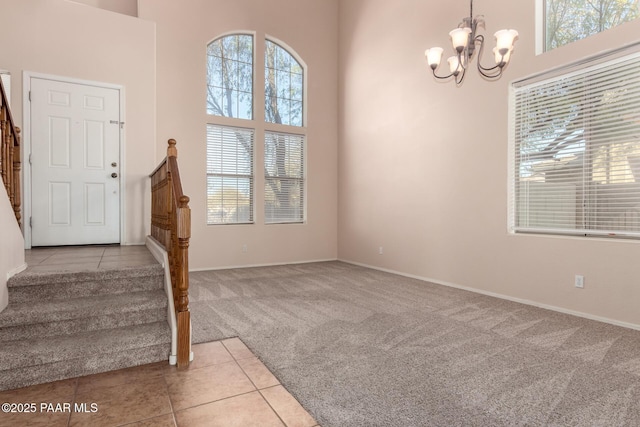 entryway with a towering ceiling, a chandelier, light carpet, and a wealth of natural light