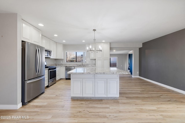 kitchen featuring stainless steel appliances, sink, pendant lighting, white cabinetry, and a kitchen island