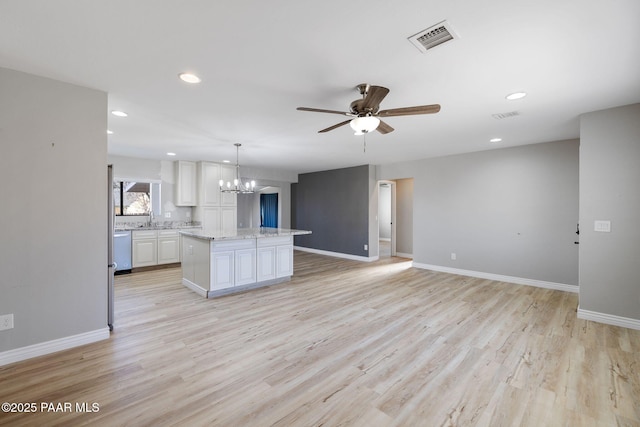 kitchen with ceiling fan with notable chandelier, a kitchen island, pendant lighting, light hardwood / wood-style flooring, and white cabinetry