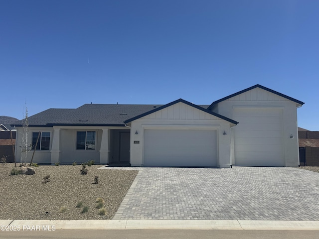 ranch-style home with a garage, a shingled roof, and decorative driveway