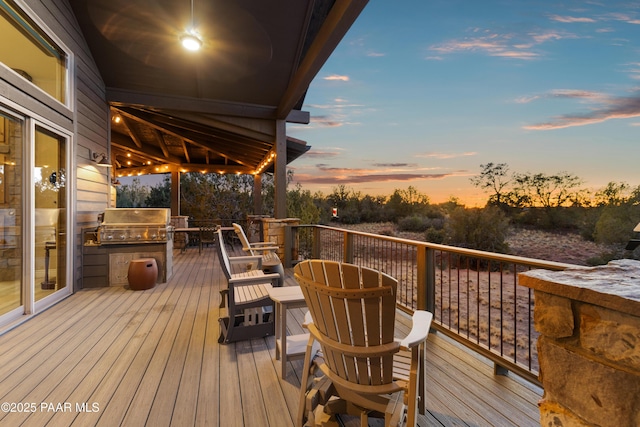 deck at dusk featuring exterior kitchen