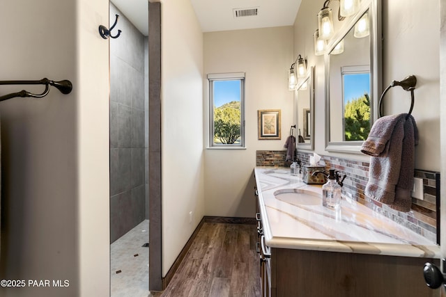 bathroom featuring decorative backsplash, a shower, wood-type flooring, and vanity