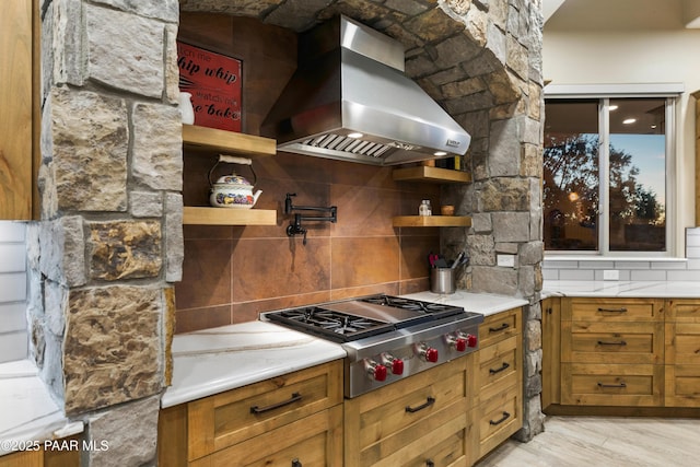 kitchen featuring extractor fan, stainless steel gas cooktop, backsplash, and light wood-type flooring