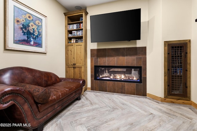 living room featuring a tiled fireplace and light parquet floors