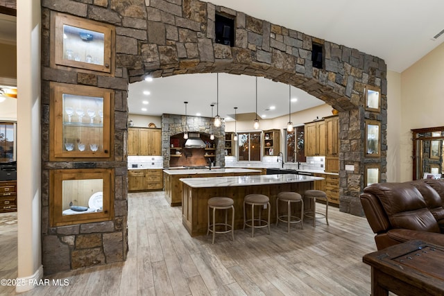 kitchen featuring pendant lighting, a center island, light hardwood / wood-style floors, a kitchen bar, and backsplash