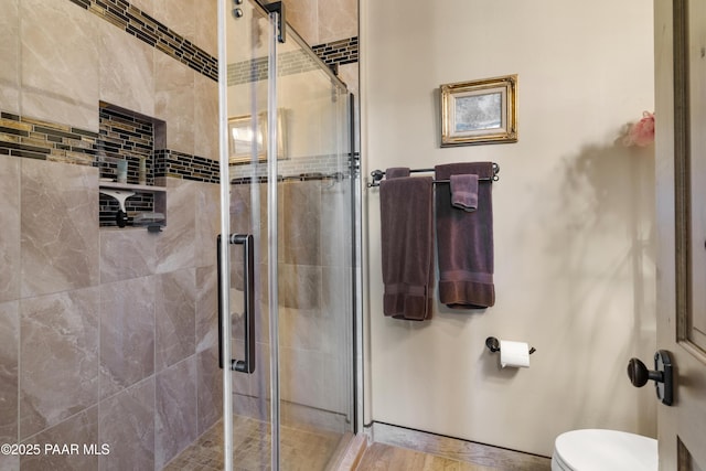 bathroom featuring a shower with shower door and toilet