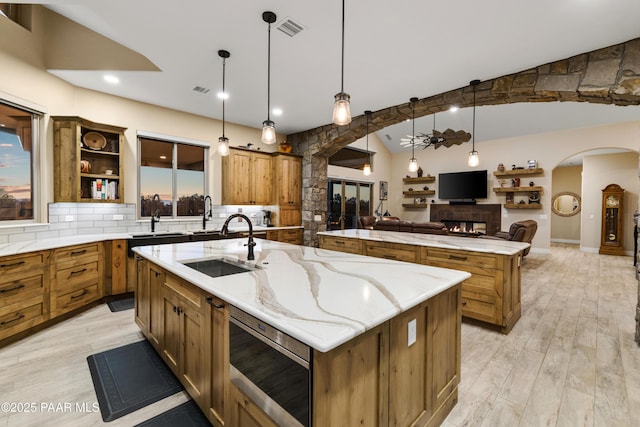 kitchen with decorative light fixtures, a large island, vaulted ceiling, light stone counters, and decorative backsplash