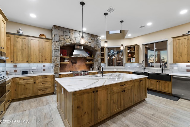 kitchen with a kitchen island with sink, light hardwood / wood-style floors, dishwashing machine, pendant lighting, and exhaust hood