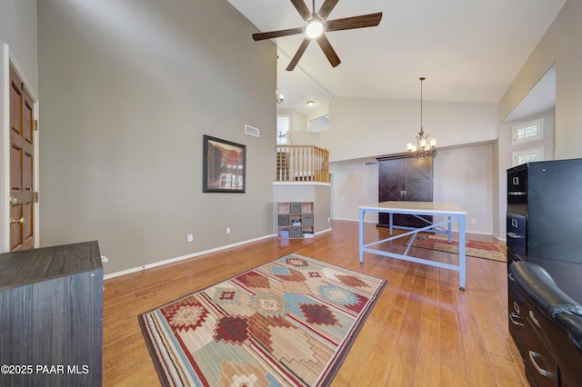 living room featuring ceiling fan with notable chandelier, hardwood / wood-style floors, and high vaulted ceiling