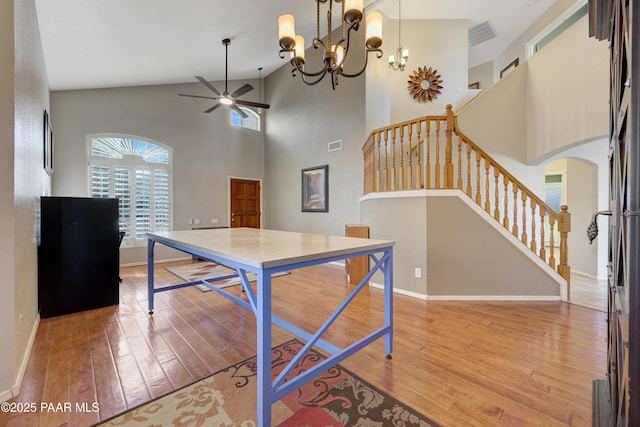 interior space with wood-type flooring, a towering ceiling, and ceiling fan