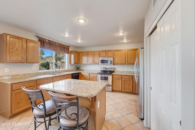 kitchen featuring light tile patterned flooring, stainless steel appliances, a center island, and light stone countertops