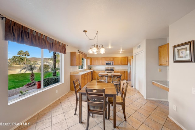 dining area with a notable chandelier, sink, and light tile patterned floors