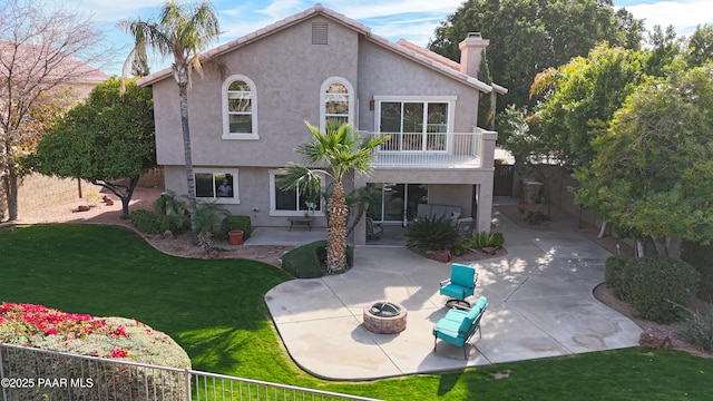 view of front facade featuring a balcony, an outdoor fire pit, a patio area, and a front lawn