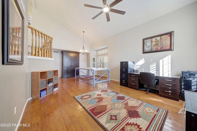 office space featuring high vaulted ceiling, ceiling fan with notable chandelier, and light hardwood / wood-style floors