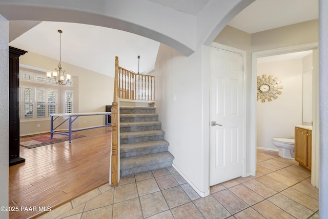 staircase featuring an inviting chandelier, lofted ceiling, and tile patterned flooring