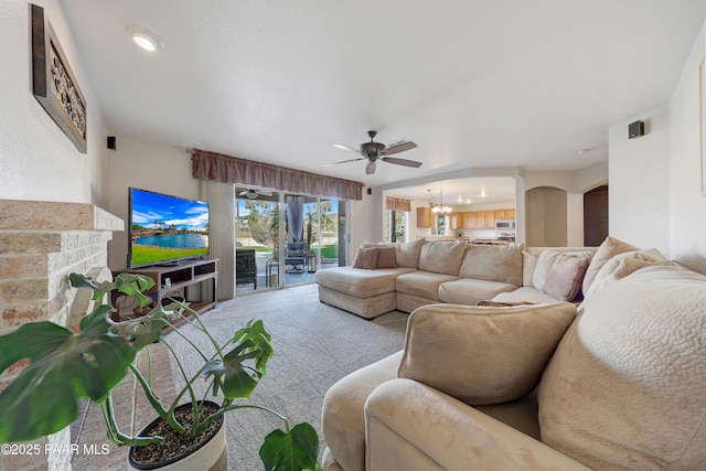 living room featuring ceiling fan with notable chandelier, a fireplace, and carpet floors