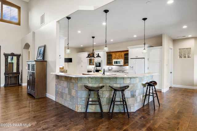 2469 W Post Oak Dr, Prescott, AZ 86305 - kitchen with white appliances, a kitchen breakfast bar, a peninsula, recessed lighting, and glass insert cabinets