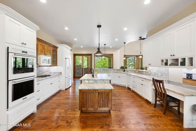 2469 W Post Oak Dr, Prescott, AZ 86305 - kitchen featuring white appliances, a peninsula, decorative backsplash, a center island with sink, and pendant lighting