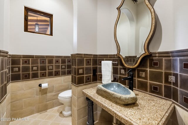 bathroom featuring tile patterned floors, sink, tile walls, and toilet