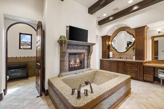 bathroom featuring beamed ceiling, vanity, and a high end fireplace