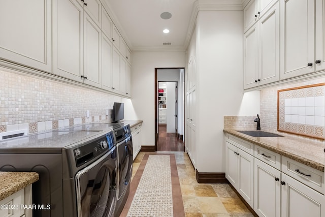 laundry area with independent washer and dryer, sink, cabinets, and ornamental molding