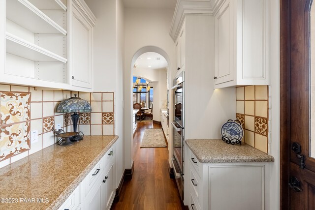 kitchen with white cabinets, backsplash, and dark wood-type flooring