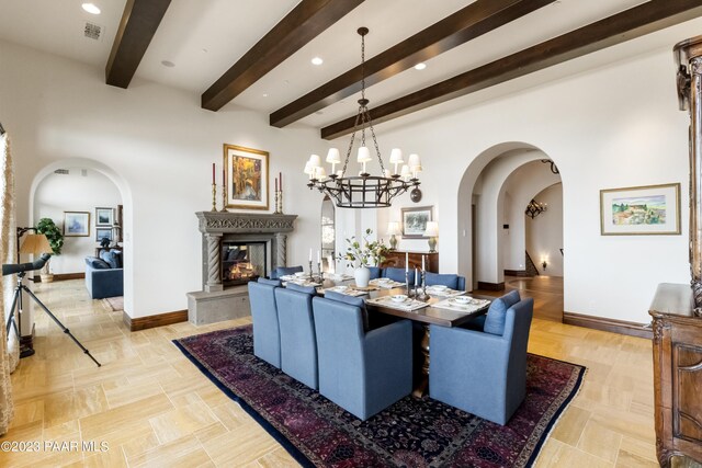 dining area with a notable chandelier, beam ceiling, and a premium fireplace