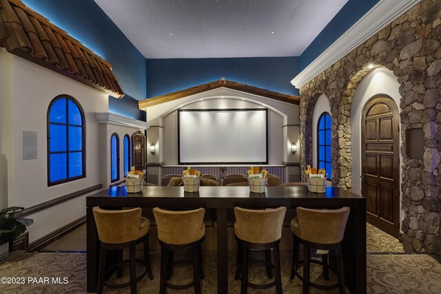 carpeted cinema room with vaulted ceiling