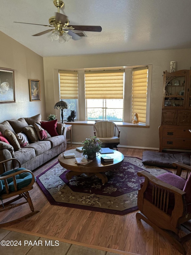 living room featuring ceiling fan, wood-type flooring, and a textured ceiling