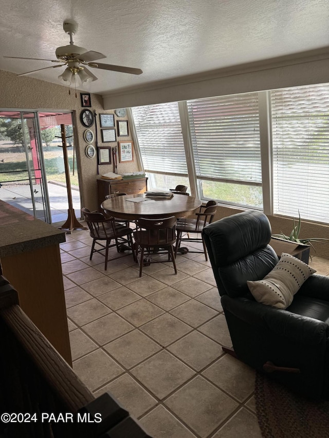 tiled dining space with ceiling fan and a textured ceiling