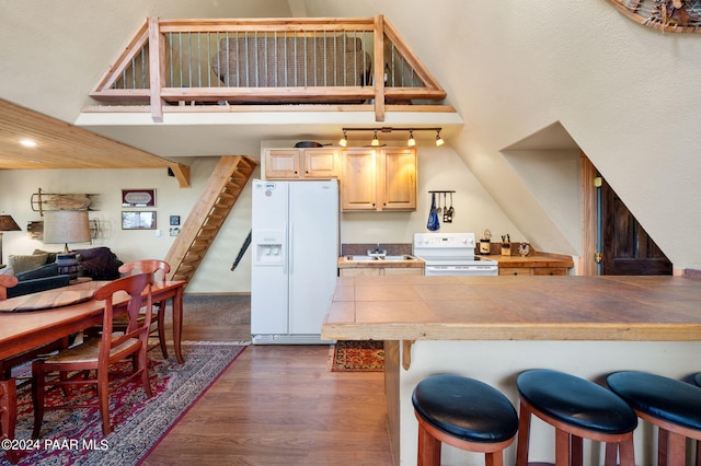 kitchen featuring white appliances, dark wood-type flooring, a kitchen breakfast bar, sink, and tile counters