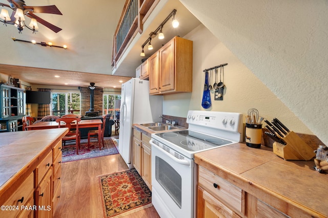 kitchen with white appliances, sink, tile countertops, light hardwood / wood-style floors, and a wood stove