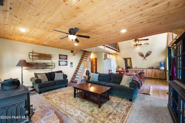 living room with a wood stove, ceiling fan, wooden ceiling, and light hardwood / wood-style floors