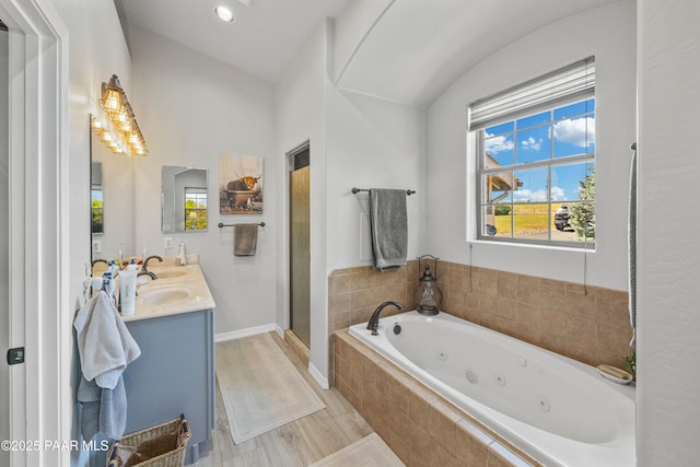 full bath with a stall shower, plenty of natural light, a tub with jets, and double vanity