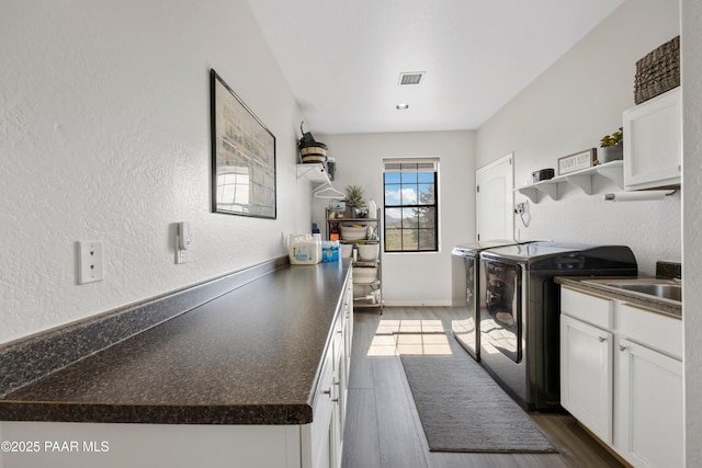 kitchen featuring open shelves, dark countertops, visible vents, white cabinetry, and independent washer and dryer