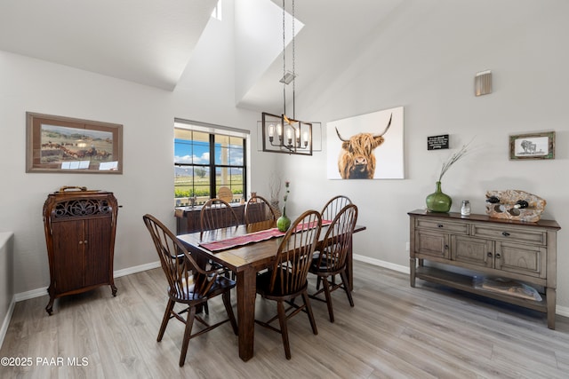 dining room with a notable chandelier, high vaulted ceiling, light wood-type flooring, and baseboards