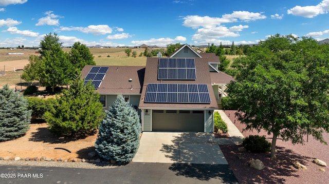 view of front of house with a garage, concrete driveway, roof with shingles, and roof mounted solar panels