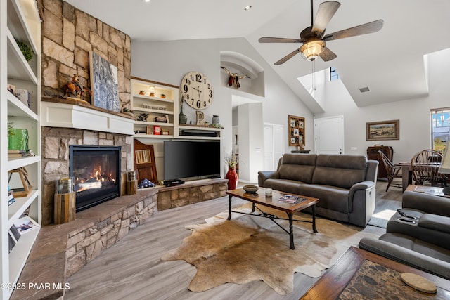 living room with ceiling fan, high vaulted ceiling, a fireplace, visible vents, and light wood-style floors