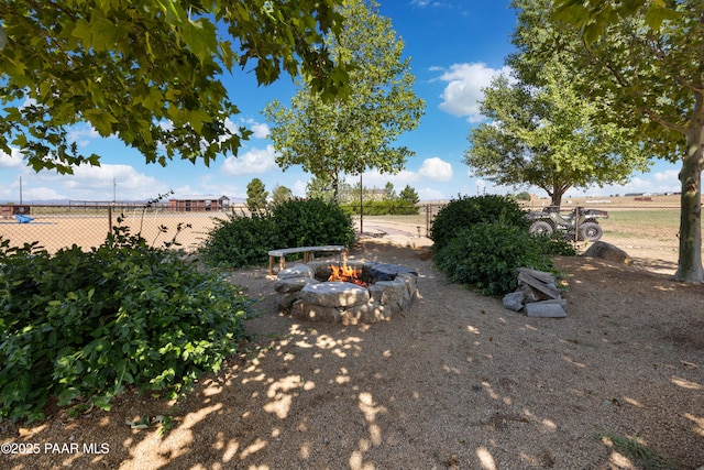view of yard featuring an outdoor fire pit, fence, and a rural view