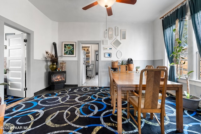 dining space with a wood stove and ceiling fan