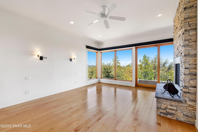 unfurnished living room with crown molding, baseboards, light wood-type flooring, and a wealth of natural light