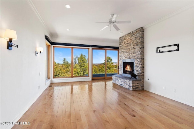 unfurnished living room featuring light wood-type flooring, a stone fireplace, and ornamental molding