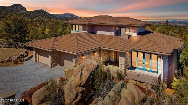 view of front facade with a mountain view, stone siding, and a tile roof