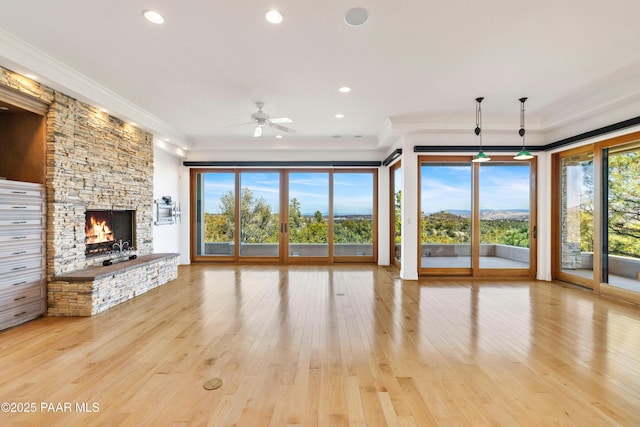 unfurnished living room with a stone fireplace, crown molding, recessed lighting, and wood finished floors